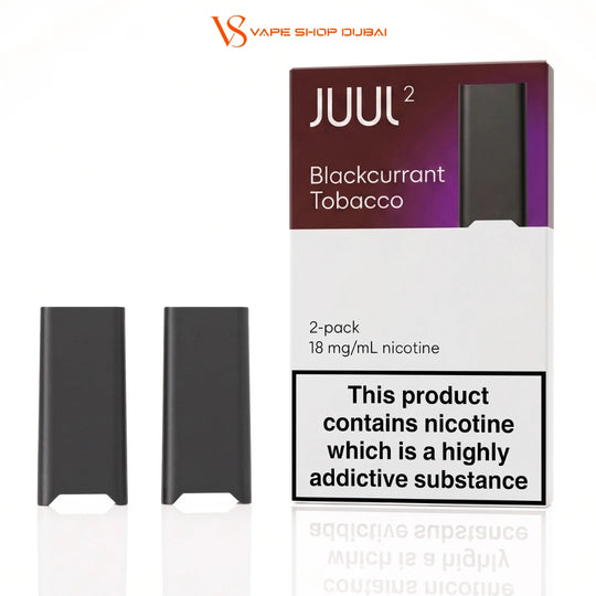 Two black JUUL 2 disposable vape devices shown next to their retail packaging box, which is labeled 'Blackcurrant Tobacco' and features a prominent nicotine warning label. The image is branded with 'VS Vape Shop Dubai' at the top.