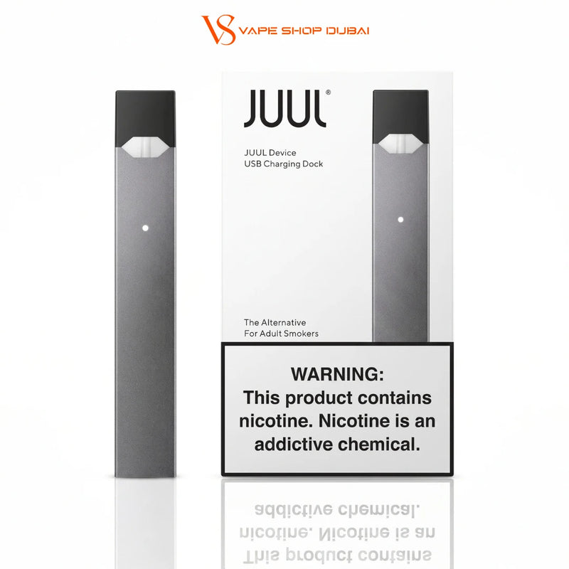 A JUUL disposable vape device and its USB charging dock packaging are shown on a white background, with a prominent nicotine warning label in front. The JUUL Shop Dubai brand logo is visible at the top.